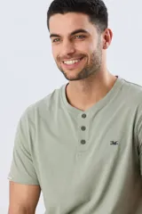 Remera básica de manga corta y cuello redondo, color bordó, con cartera de botones en el pecho y pequeño bordado al tono.