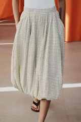 Falda midi de tiro medio color beige con estampado de cuadros finos oscuros. Presenta pliegues en la cintura y bajo abullonado con acabado evasé, de Zara Woman Collection.