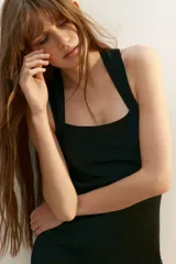 Vestido corto negro de punto, con escote cuadrado al frente y breteles anchos que se cruzan formando una 'X' en la espalda.