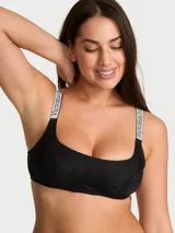 Bralette negro de encaje con diseño sin forro y sin aros, escote redondo pronunciado y tirantes ajustables con pedrería y monograma de la marca.