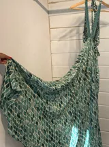 Vestido largo con estampado de hojas en tonos verde y blanco, con escote halter y espalda descubierta.