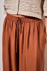 Babucha de viscosa color ladrillo, de tiro alto con cintura elástica fruncida y cordón ajustable del mismo tejido, con diseño fluido y puños ajustados en los tobillos.