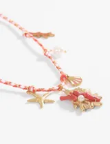 Collar con cordón celeste y blanco trenzado, con dijes metálicos dorados y celestes con motivos marinos: estrella de mar, pez, alga y caracol. Cierre con nudo corredizo.