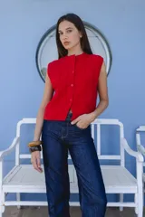 Chaleco tejido rojo con textura en relieve y botones en la delantera, sin mangas.