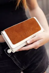 Billetera mediana de cuero color natural con tapa de cuero gamuzado color marrón y logo grabado.