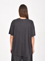 Remera de algodón color marrón con efecto lavado, de corte holgado y manga corta. Presenta un estampado frontal con temática espacial que incluye planetas, estrellas y la frase 'Into the cosmos'.