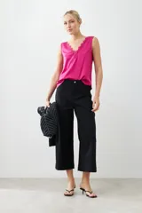 Top satinado color fucsia con escote en V y detalles de encaje en el borde del escote. Sin mangas y de corte holgado.