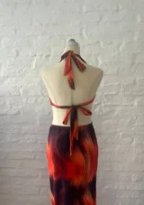 Vestido largo con estampado abstracto en tonos naranja y azul, con escote halter y aberturas laterales en la cintura.