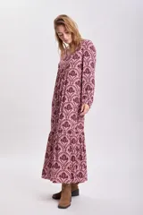 Vestido largo de corte holgado con estampado floral en tonos rosa y marrón. Tiene escote en V, mangas largas abullonadas y cinturón marrón de cuero sintético.