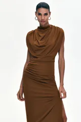Vestido midi en punto elástico marrón, con cuello drapeado alto, hombreras y diseño sin mangas. Presenta frunces en los hombros y en la cadera con falda entallada.