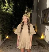 Vestido corto blanco de lino, con cuello redondo con detalle de fruncido y mangas cortas abullonadas. El calce es holgado tipo evasé con un pequeño volante en el ruedo.