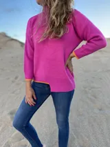 Sweater fucsia de tejido de punto con cuello alto y mangas largas. Presenta ribete naranja en puños y ruedo.