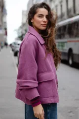Chaqueta de lana afieltrada en color amarillo mostaza, con cuello camisero, cierre frontal con broches a presión y bolsillos delanteros. Presenta un diseño de espalda con apertura para mayor movimiento.