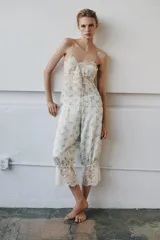 Pantalón bombacho de tiro medio y cintura elástica, confeccionado en viscosa con estampado floral y rayas sutiles. Presenta bajo ajustable con lazada y aplicación de encaje contrastante en el ruedo.