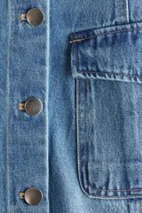 Vestido midi de denim de algodón con breteles anchos, escote cuadrado, botonadura frontal y múltiples bolsillos con solapa. Presenta un cuerpo entallado y falda acampanada con costuras visibles.