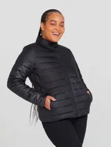 Campera puffer color crudo, con cuello alto y cierre frontal. Tiene bolsillos laterales y diseño matelassé horizontal.