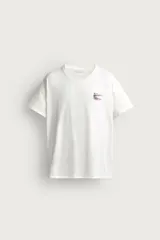 Camiseta relaxed fit de color blanco con efecto lavado, cuello redondo y manga corta. Presenta un pequeño estampado a contraste en el pecho izquierdo.