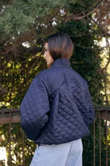 Campera acolchada de color azul marino, con diseño de rombos, cuello tipo chal y cierre frontal con botones grandes al tono. Presenta puños y ruedo acanalados, y bolsillos laterales.