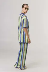 Pantalón largo de tejido crochet con rayas verticales en tonos azul, verde, marrón y blanco.