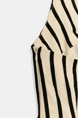 Vestido midi de corte globo con estampado de rayas verticales, cuello halter anudado, escote en pico y espalda descubierta. Presenta bajo abullonado con elástico interior y cierre lateral con cremallera oculta.
