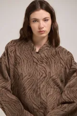 Campera tipo bomber de corte holgado con diseño estampado de cebra en tonos marrones. Presenta cuello redondo, cierre frontal con botones a presión y mangas largas amplias.