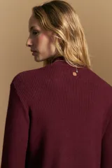 Polera de tejido acanalado color bordó, con cuello alto y diseño geométrico en relieve que estiliza la figura. Presenta un ajuste al cuerpo y mangas largas.
