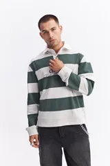 Polo de manga larga con diseño de rayas horizontales anchas en color marrón y crema. Presenta cuello camisero blanco con cartera de botones y estampado frontal con texto decorativo y logo de la marca.