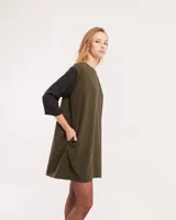 Vestido corto negro con mangas 3/4 verdes, cuello bote y bolsillos laterales.