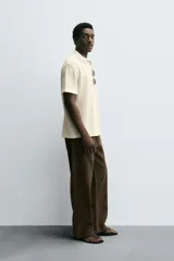 Polo de manga corta color marrón oscuro, confeccionado en tejido waffle de algodón, con cuello solapa y abertura frontal.