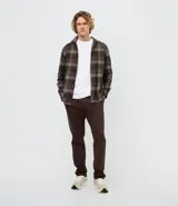 Pantalón slim de sarga lavada para hombre, de corte ajustado y color beige, con bolsillos laterales y traseros, trabillas para cinturón y cierre frontal con botón y cremallera.