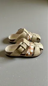Sandalias de cuero color beige con arte pintado a mano en tonos marrones y blancos, hebilla lateral y suela de corcho y goma.