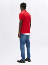 Chomba roja de corte slim, con cuello polo y cartera de dos botones. Logo de Tommy Hilfiger bordado en el pecho.