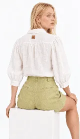 Camisa clásica de lino natural color blanco, con mangas abullonadas tres cuartos y delicados bordados artesanales de flores en el frente.