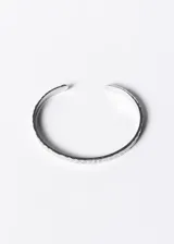 Pulsera esclava abierta de acero quirúrgico con textura martillada.