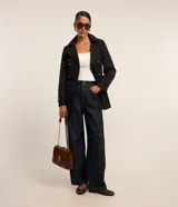 Trench coat de corte sastrero color beige, con cuello solapa, cierre frontal de doble botonadura y acabado satinado.