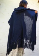 Ruana tejida en cinta de algodón, con diseño de capucha integrada y terminación con flecos en el ruedo.