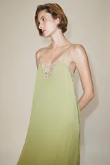 Vestido midi confeccionado en hilatura de viscosa, de color verde con detalles de encaje a contraste en el escote y el bajo. Cuenta con escote recto y tirantes finos ajustables.