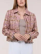 Chaqueta de tweed en tonos rosados, marrones y blancos, con hilos metalizados y lentejuelas brillantes. Presenta cuello camisero, cierre frontal con botones metálicos dorados, bolsillos frontales en el pecho, mangas largas y terminaciones desflecadas.