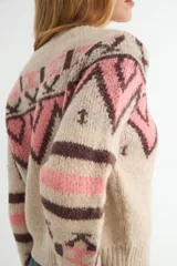 Saco tejido con diseño geométrico estilo inca, en tonos beige, rosa y marrón. Presenta cuello redondo, cierre frontal con botones y puños acanalados.