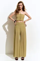 Top strapless cropped dorado, en tejido de punto acanalado con hilos brillantes, corte ajustado, con cordones cruzados en el frente y tiras halter finas para atar al cuello.