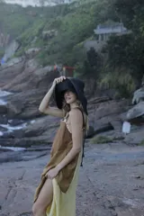 Vestido midi de lino color salmón, de corte amplio y silueta holgada. Presenta diseño con cortes irregulares y detalles de pasamanería en el escote y costuras. Cuenta con breteles dobles tipo cuerda y ruedo asimétrico.