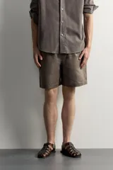 Bermuda de lino negro de corte relaxed fit, con cintura elástica ajustable mediante cordón y bolsillos frontales.
