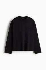 Remera de manga larga en punto pesado, color negro, con cuello redondo ribeteado, hombros caídos y bajo recto. Corte oversized para una silueta amplia y relajada.