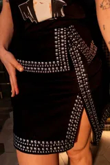 Minifalda negra con tachas plateadas y abertura lateral.