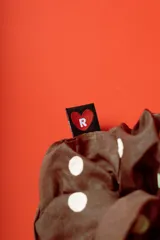 Colitapelo scrunchie de tela marrón con lunares amarillos.