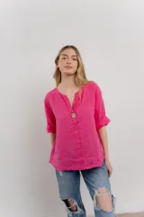 Blusa holgada de lino color verde brillante, con cuello mao abierto y manga corta enrollada. Presenta bordados estilo paisley en tono a tono y un botón de madera en el escote.