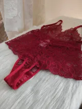 Body de encaje color rojo con escote pronunciado, breteles regulables y diseño tipo tanga en la parte inferior.