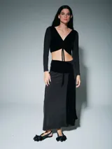 Falda larga de corte recto en color negro, confeccionada en tejido fluido con un detalle de faja drapeada en terciopelo negro en la cintura que cae lateralmente.
