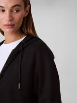 Buzo cropped con capucha y cierre frontal completo, confeccionado en punto milano. Presenta mangas largas con puños acanalados y dobladillo inferior también acanalado, ofreciendo una silueta estructurada y moderna.