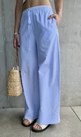 Pantalón pijamero celeste a rayas verticales blancas, de corte ancho y cintura con cordón ajustable.